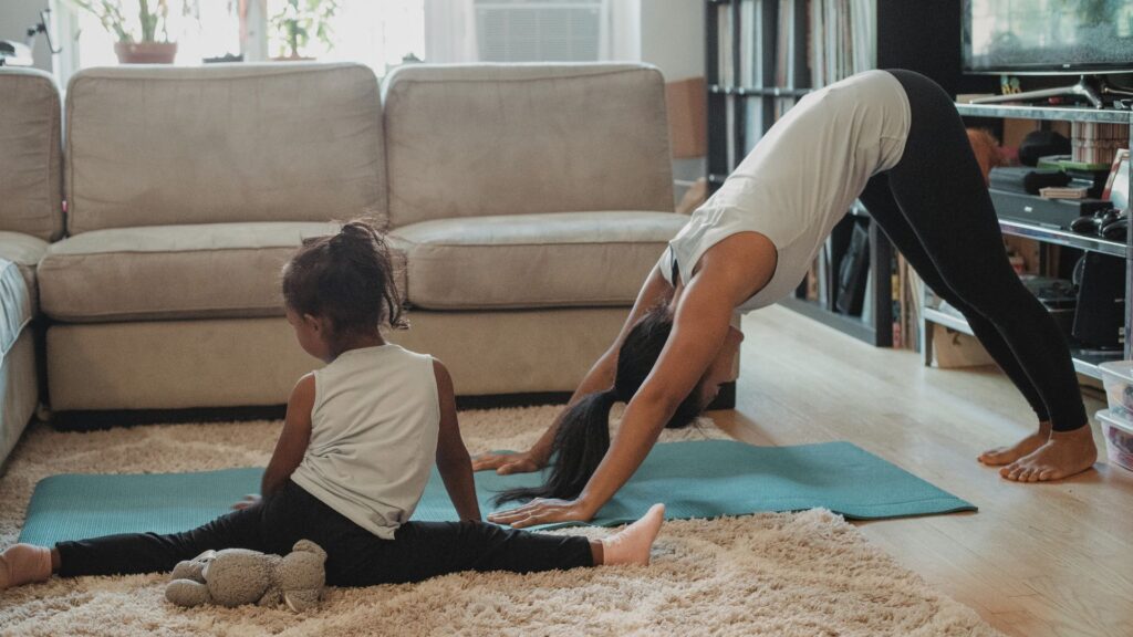 Frau macht Yoga Zuhause mit Kind daneben