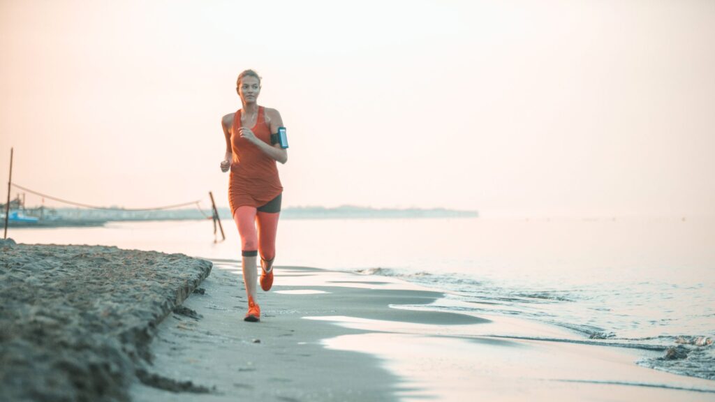Frau joggt am Strand - Symbolbild für eine minimalistische Morgenroutine