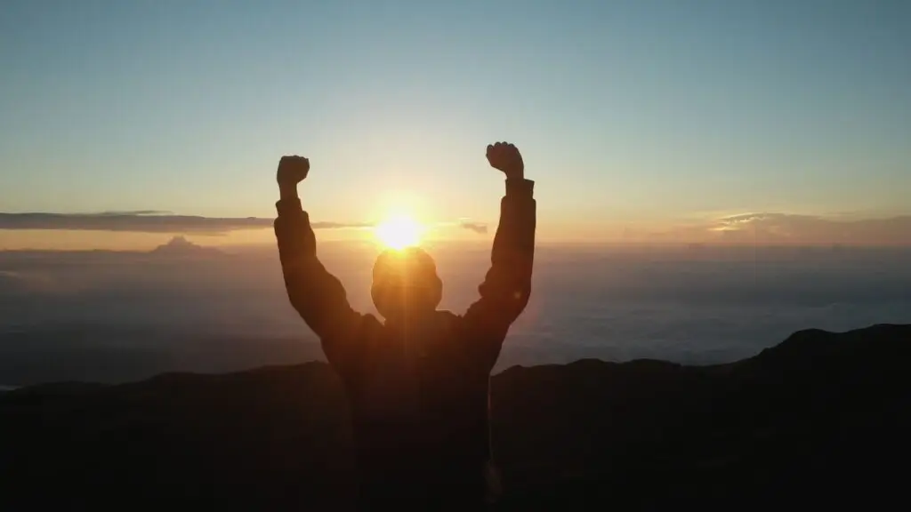 Mann auf Berg schaut in den Sonnenaufgang