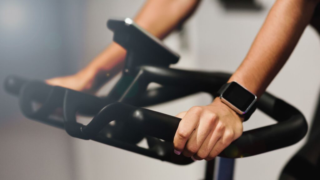 Frau auf Exercise Bike mit Smartwatch am Handgelenk