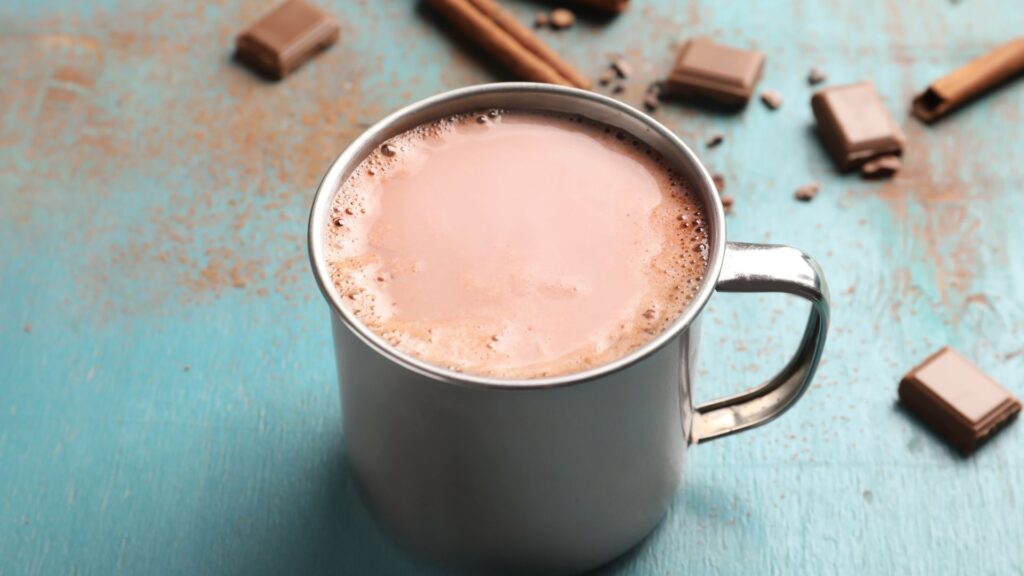Tasse mit Smaints Mushroom Cacao auf einem Tisch mit Kakaostücke und Zimt