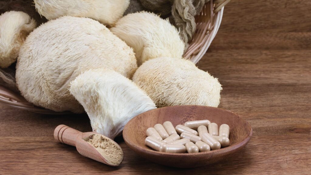 Lions Mane Vitalpilze auf einem rustikalen Holzbrett mit Kapseln daneben