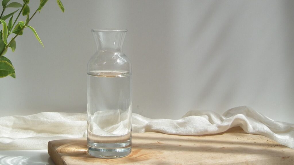 Eine Glaskaraffe mit Wasser auf einem schlichten Holzbrett