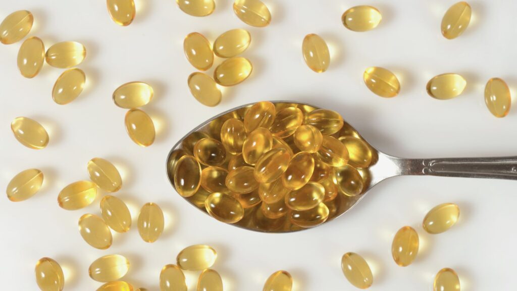 Omega-3 Fischöl Kapseln auf einem Löffel - Supplement als Alternative zu Fisch