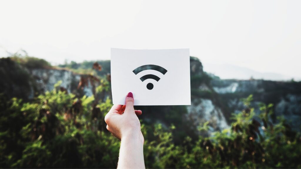 Ausschnitt aus Papier mit EMF-Symbolen vor natürlichem Hintergrund – symbolisiert den Kontrast zwischen künstlicher Strahlung und natürlichem Gleichgewicht