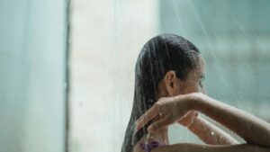 Frau unter der Dusche mit kaltem Wasser – Visualisierung einer kalten Dusche am Morgen