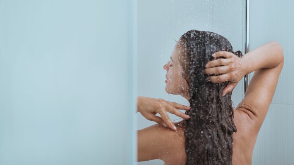 Frau genießt eine kalte Dusche – gesundes Biohacking-Ritual für mentale Stärke