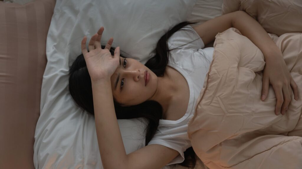 Frau liegt abends wach im Bett - Stress und Nervensystem im Alltag