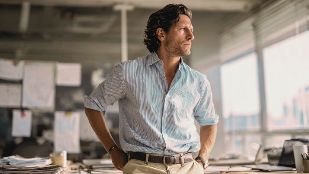 Mann im Büro im Morgenlicht blickt nachdenklich aus dem Fenster – gesund bleiben ab 30 durch bewusste Lebensführung