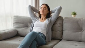 Frau sitzt entspannt auf Sofa - Regeneration und Balance des Nervensystems