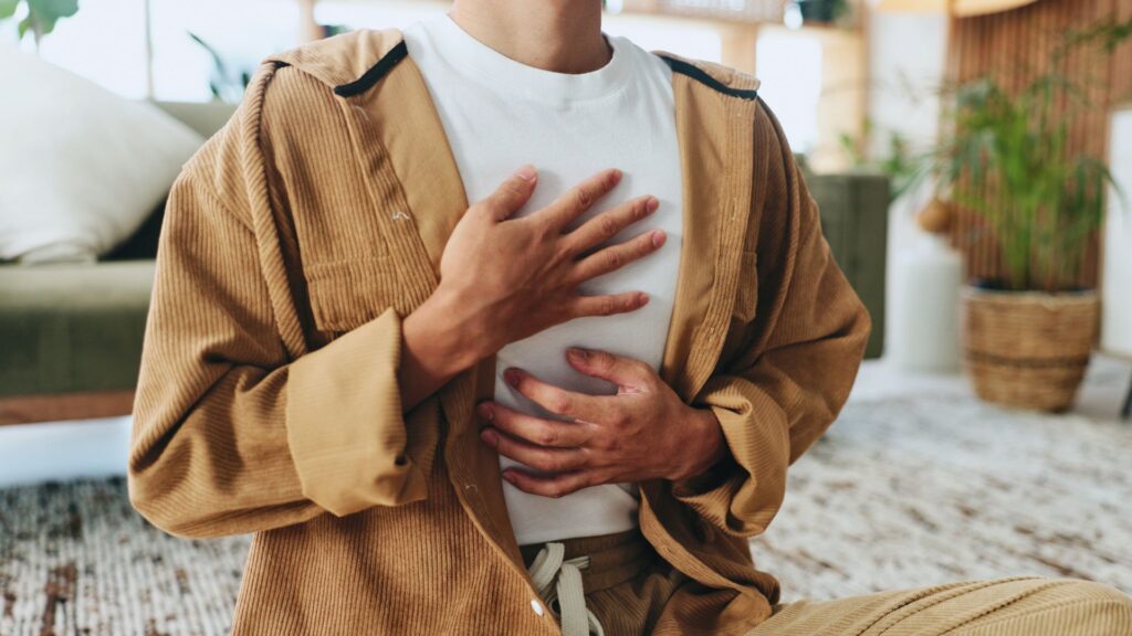Mann mit Haenden auf der Brust atmet tief ein um sein Nervensystem aktiv zu beruhigen