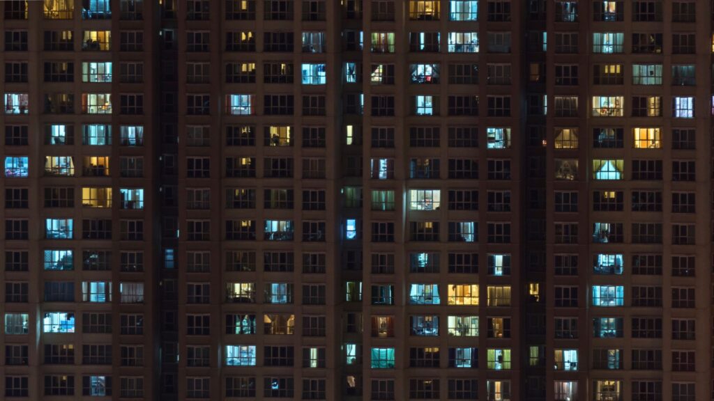 Wohnhaus bei Nacht mit vielen hellen Fenstern und künstlichem Licht